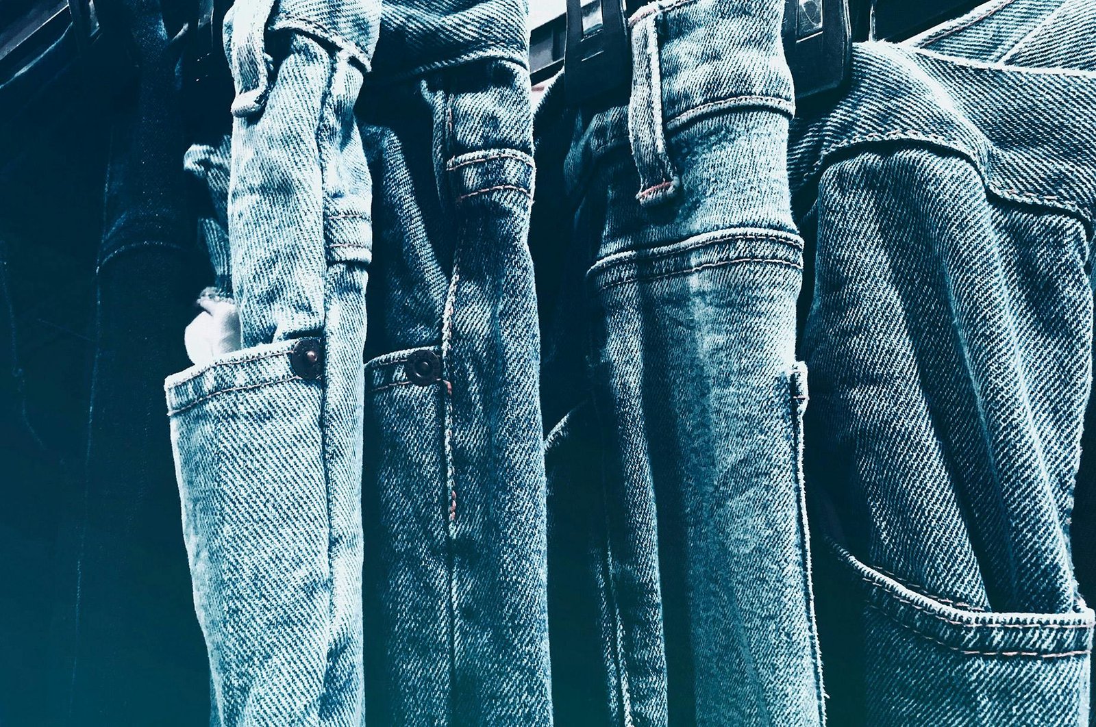 A collection of blue denim jeans hanging closely on a rack in a retail store.